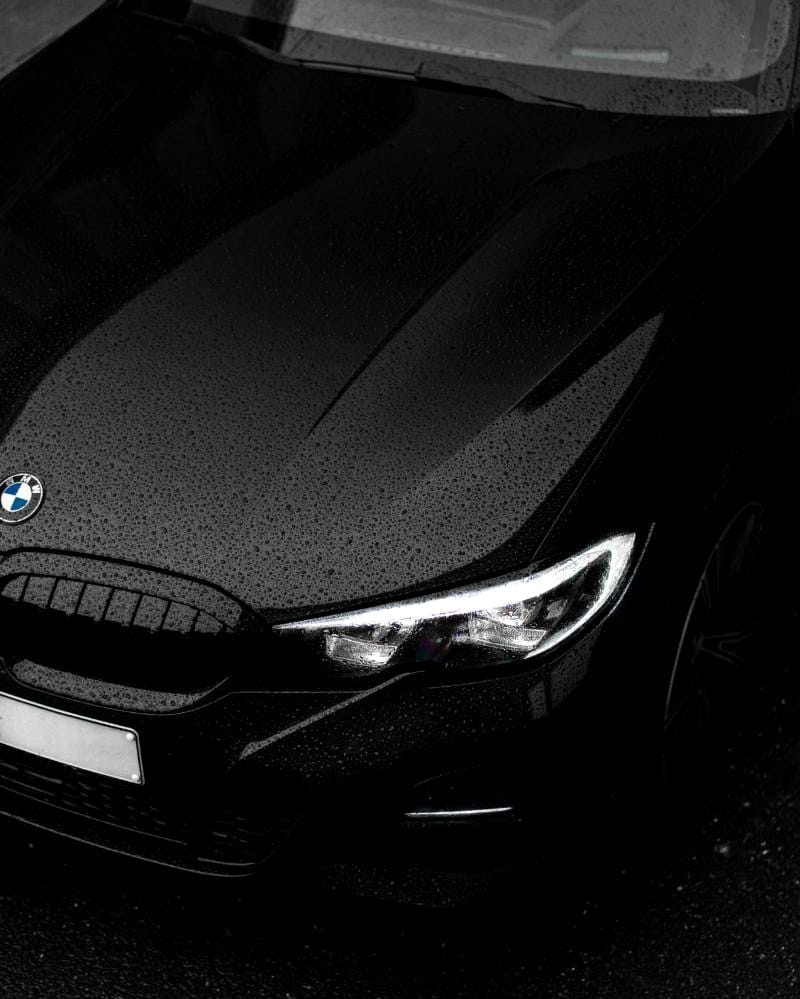 Fekete BMW motorháztetője esőcseppekkel és LED fényszóróval