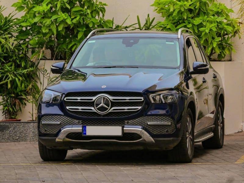 Sötétkék Mercedes-Benz szabadidő-autó szemből, térköves udvaron